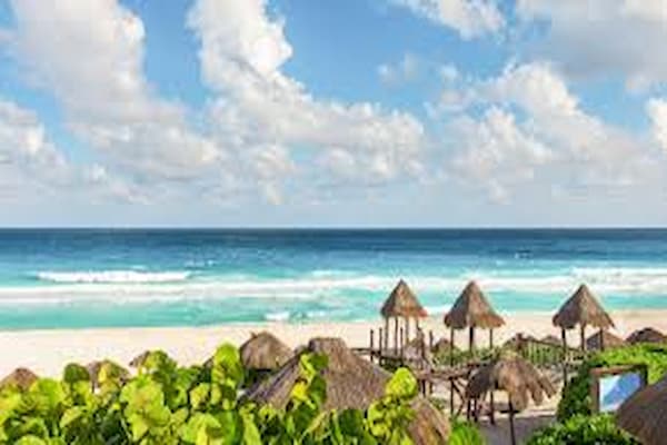 White sandy beach with palm trees and beachgoers in Cancun