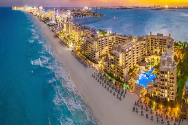 Cancun hotel zone at dusk with illuminated buildings along the coastline