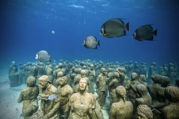 Underwater sculptures at MUSA museum with tropical fish swimming around